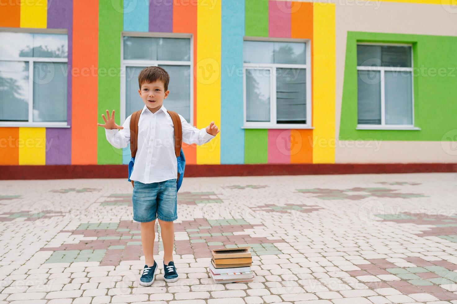 retour à école. content souriant garçon dans des lunettes est Aller à école pour le premier temps. enfant avec sac à dos et livre en plein air. début de cours. premier journée de tomber photo