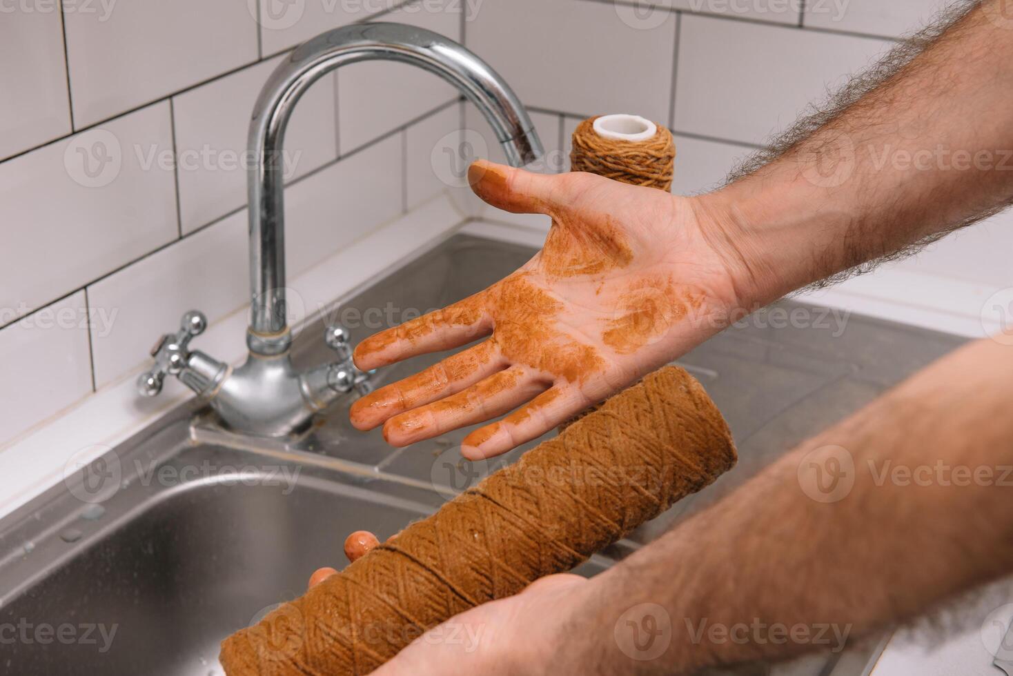 main en portant sale l'eau filtre cartouche plus de le couler. marron coloration. preuve de contamination de robinet l'eau avec le fer cations photo