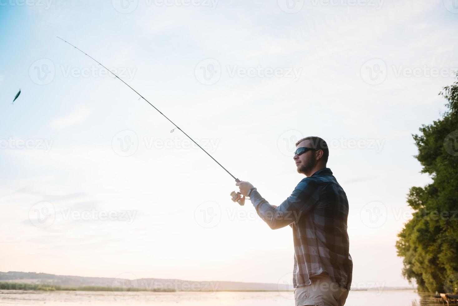 pêcheur homme pêche avec filage barre sur une rivière banque à brumeux brumeux lever du soleil. pêcheur avec filage. filage concept. photo