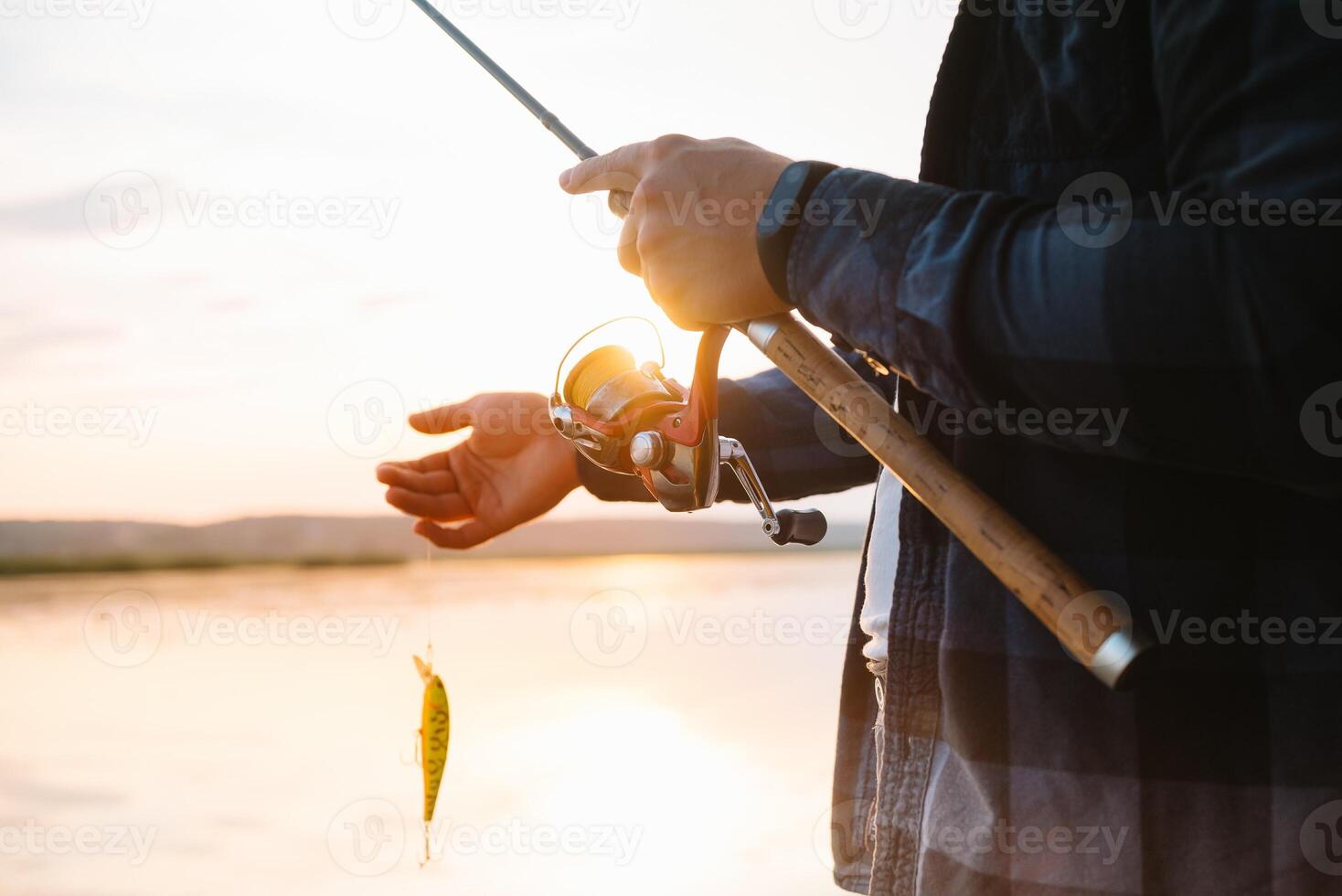 le du pêcheur mains, détient le filage canne à pêche, tourne le bobine gérer. loisir et activité. photo