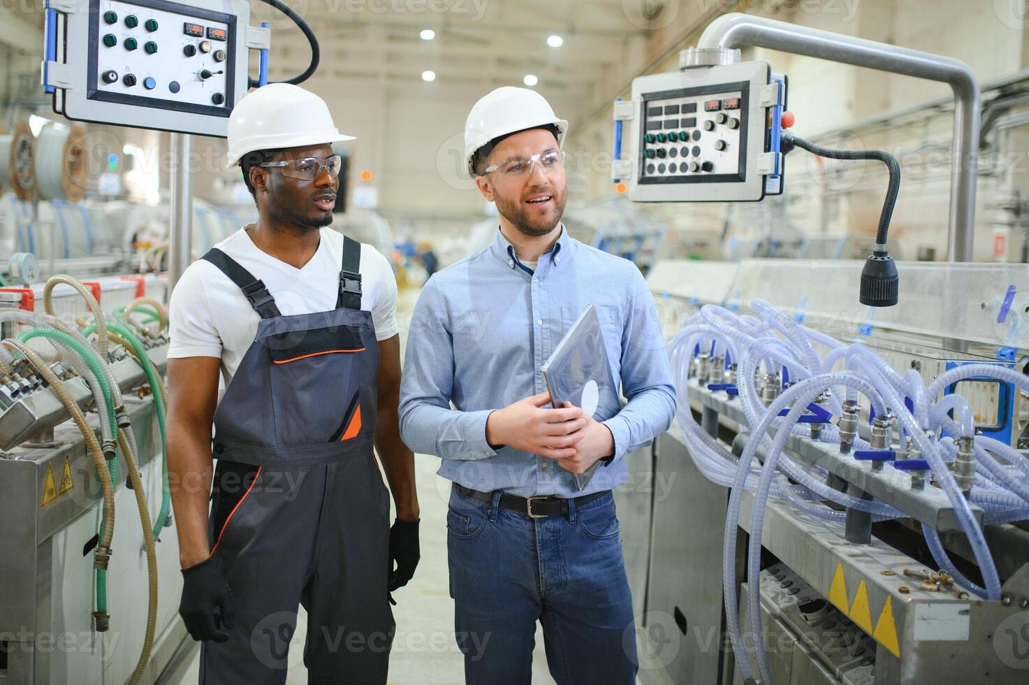 deux diverse professionnel lourd industrie ingénieurs portant sécurité uniforme et difficile Chapeaux travail sur portable photo