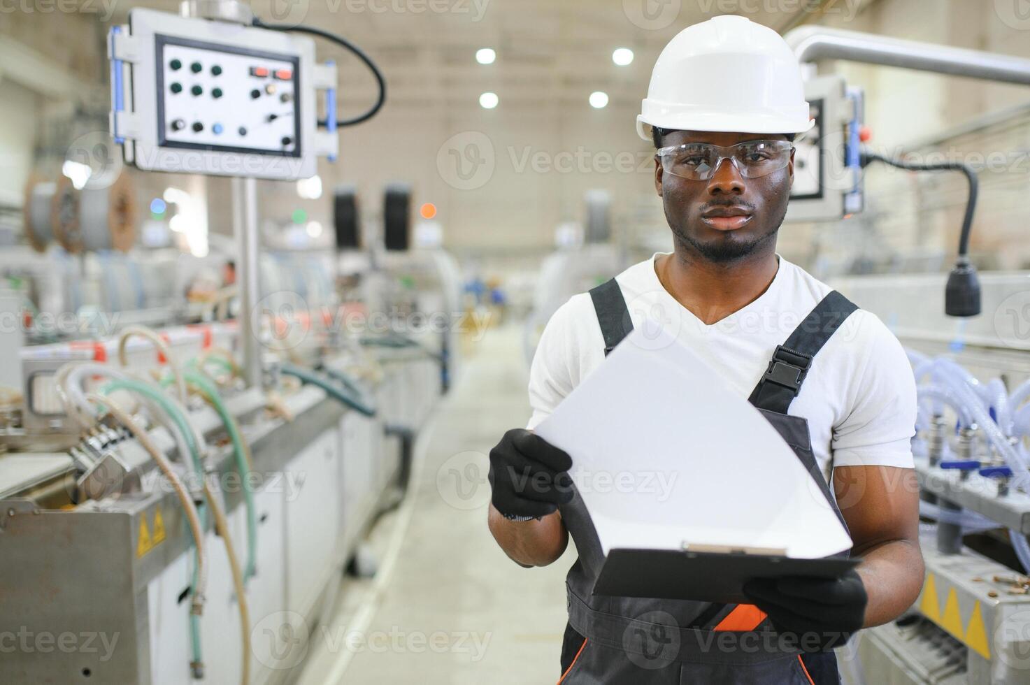 portrait de africain américain Masculin ingénieur dans uniforme et permanent dans industriel usine photo