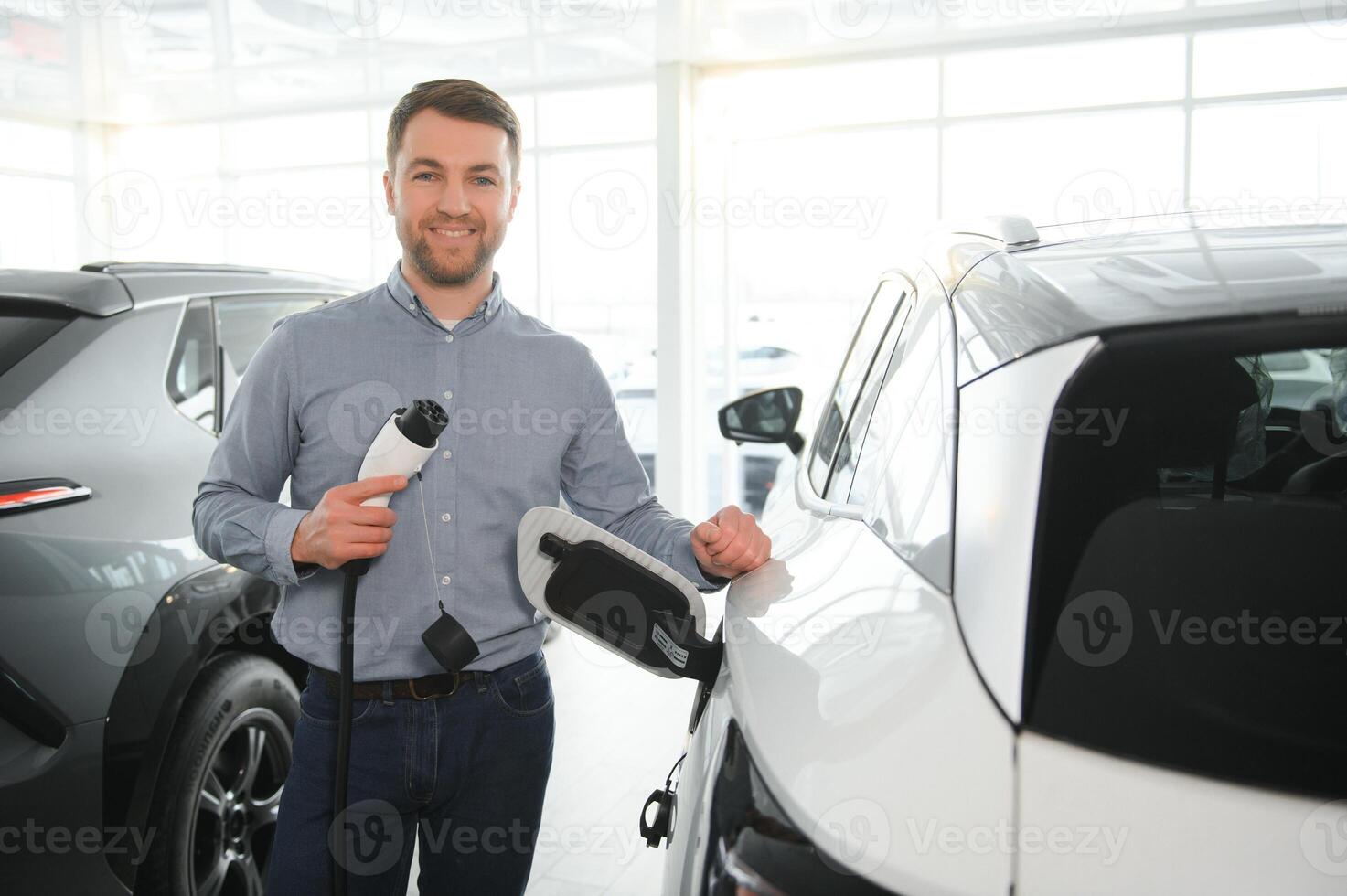 barbe homme en essayant une Nouveau mise en charge câble avec une voiture mise en charge station à le moteur concession. concept de achat électrique véhicule. intelligent écologique vivant photo