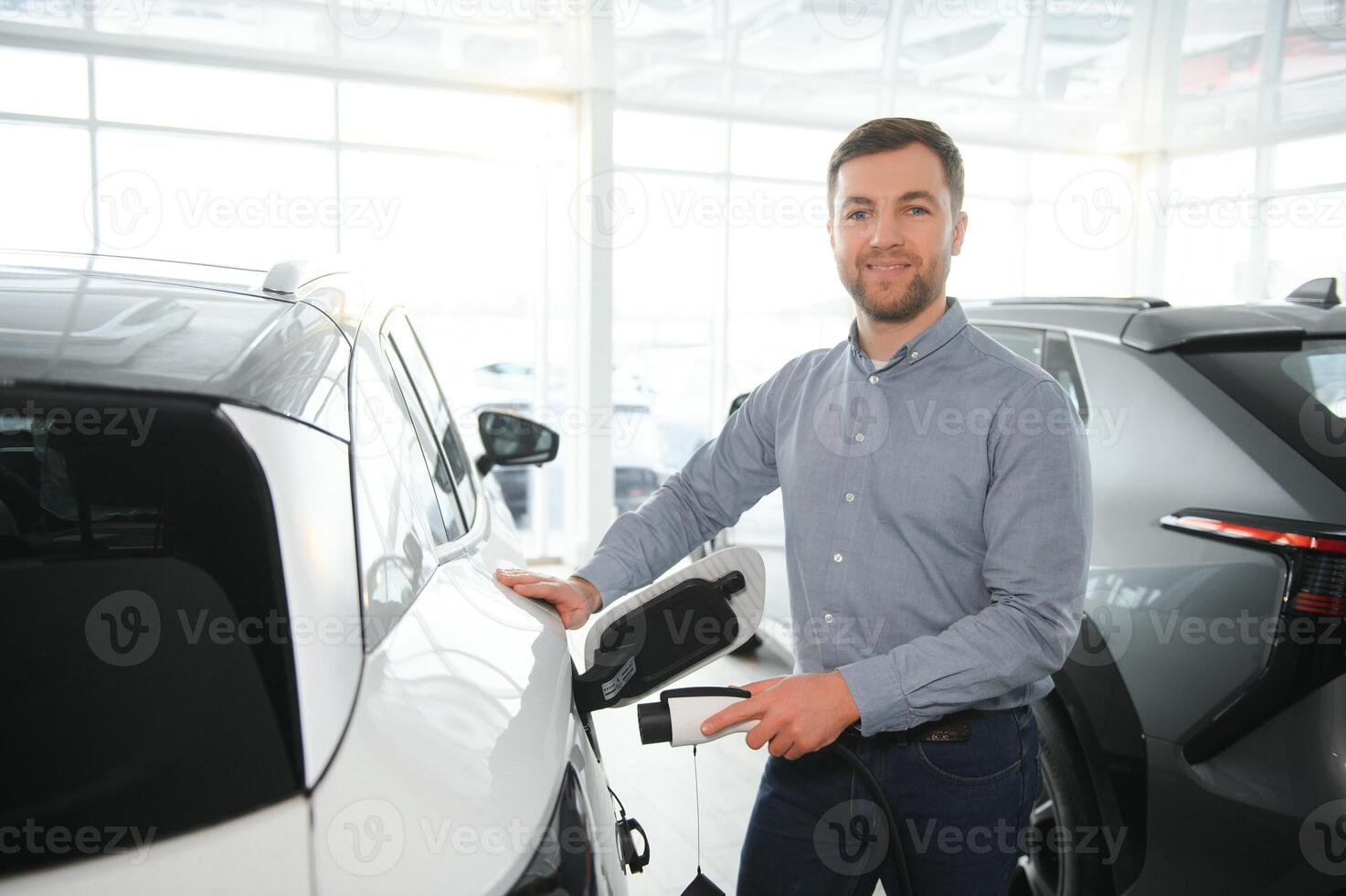 barbe homme en essayant une Nouveau mise en charge câble avec une voiture mise en charge station à le moteur concession. concept de achat électrique véhicule. intelligent écologique vivant photo