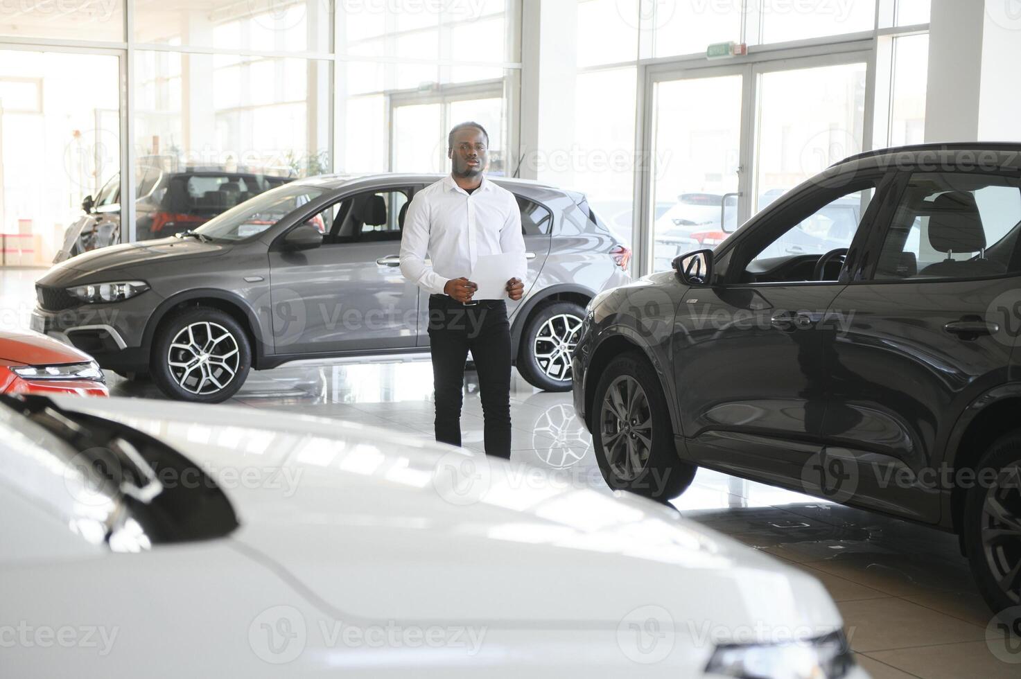 voitures concession concept. auto vendeur afro homme permanent dans voiture centre photo