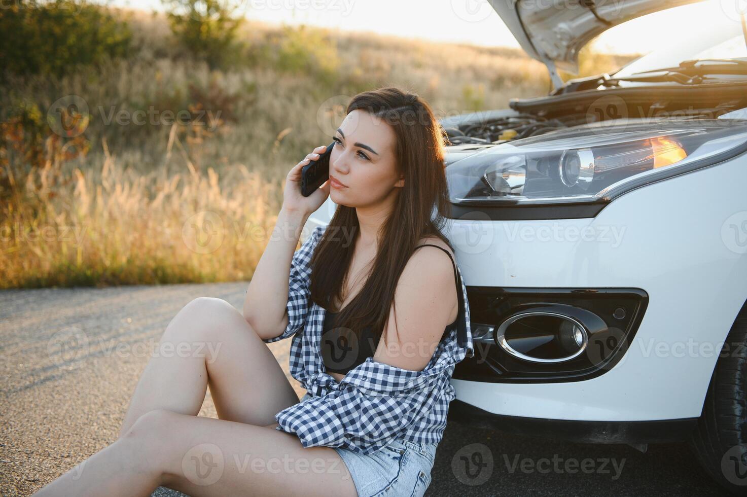 Jeune sexy femme avec cassé voiture appel sur le cellule téléphone. photo