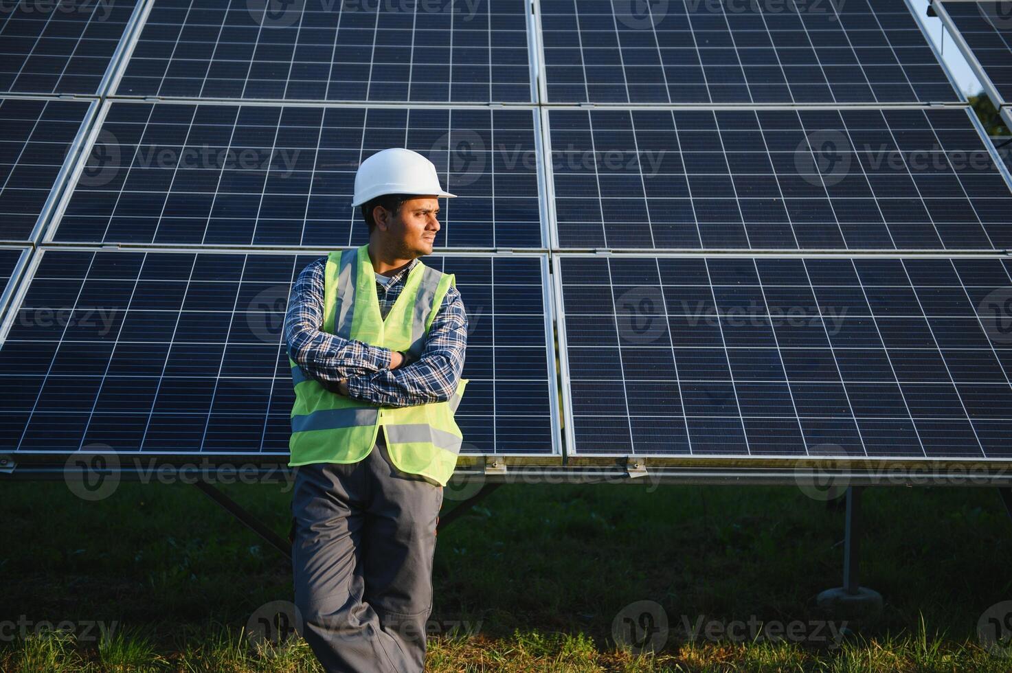 portrait de Jeune Indien homme technicien portant blanc difficile chapeau permanent près solaire panneaux contre bleu ciel. industriel ouvrier solaire système installation photo