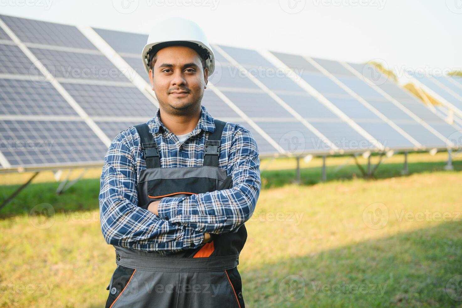 portrait de Jeune Indien homme technicien portant blanc difficile chapeau permanent près solaire panneaux contre bleu ciel. industriel ouvrier solaire système installation photo