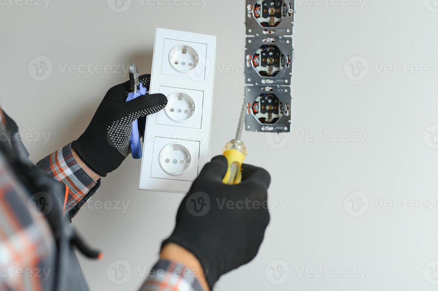 sur de soi professionnel électricien dans uniforme en utilisant Tournevis tandis que remplacer une prise dans appartement après rénovation travail. photo