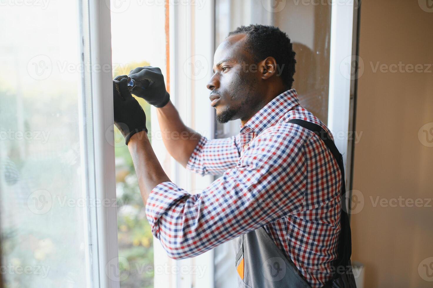 Beau Jeune africain américain homme installation baie fenêtre dans Nouveau maison construction site photo