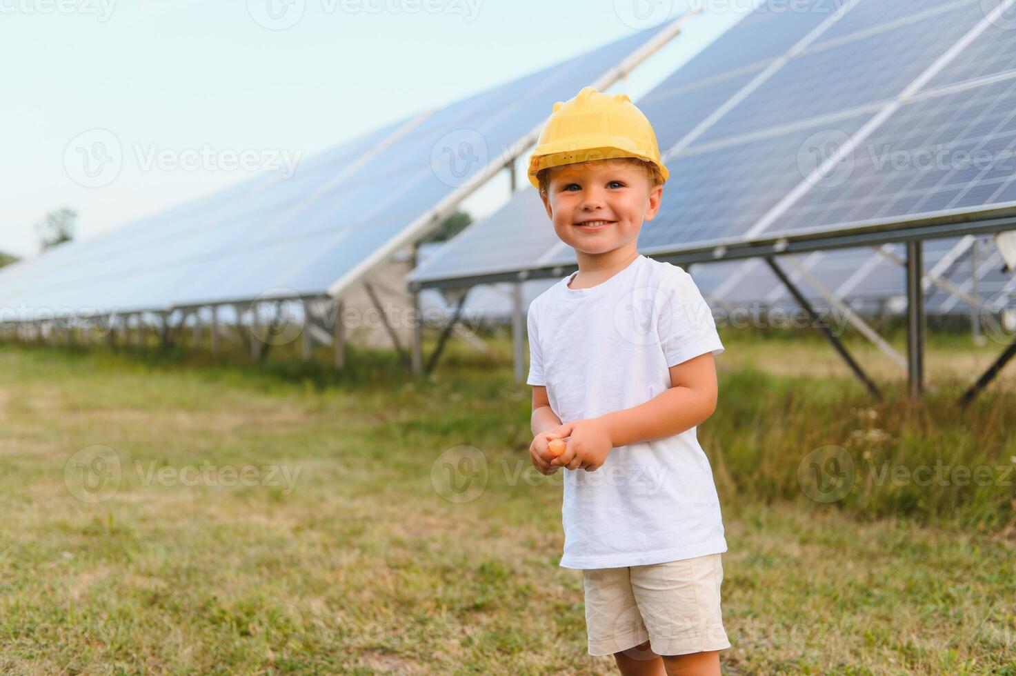 portrait de une enfant près le solaire panneaux. une peu garçon dans une protecteur casque près solaire panneaux avec le sien main. tournage à une solaire Puissance plante. écologique cultiver. solaire Puissance gare. gens photo