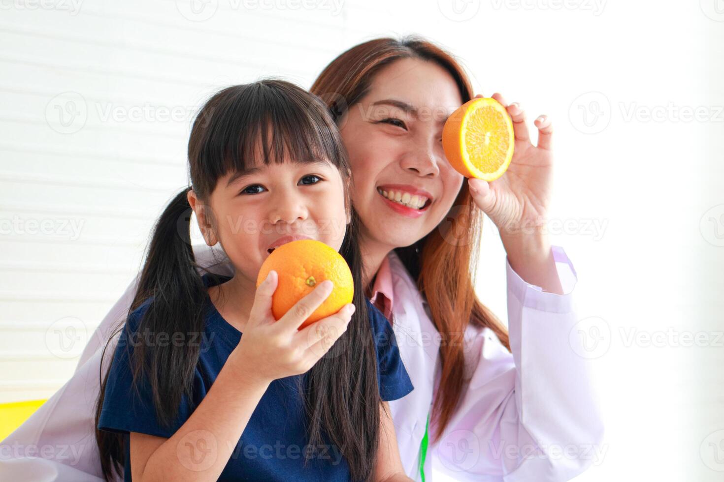 nutrition pour âge scolaire les enfants. une magnifique nutritionniste ou médecin avec une peu fille en portant un orange. choisir le droite nourriture selon à le âge de le enfant pour bien santé photo