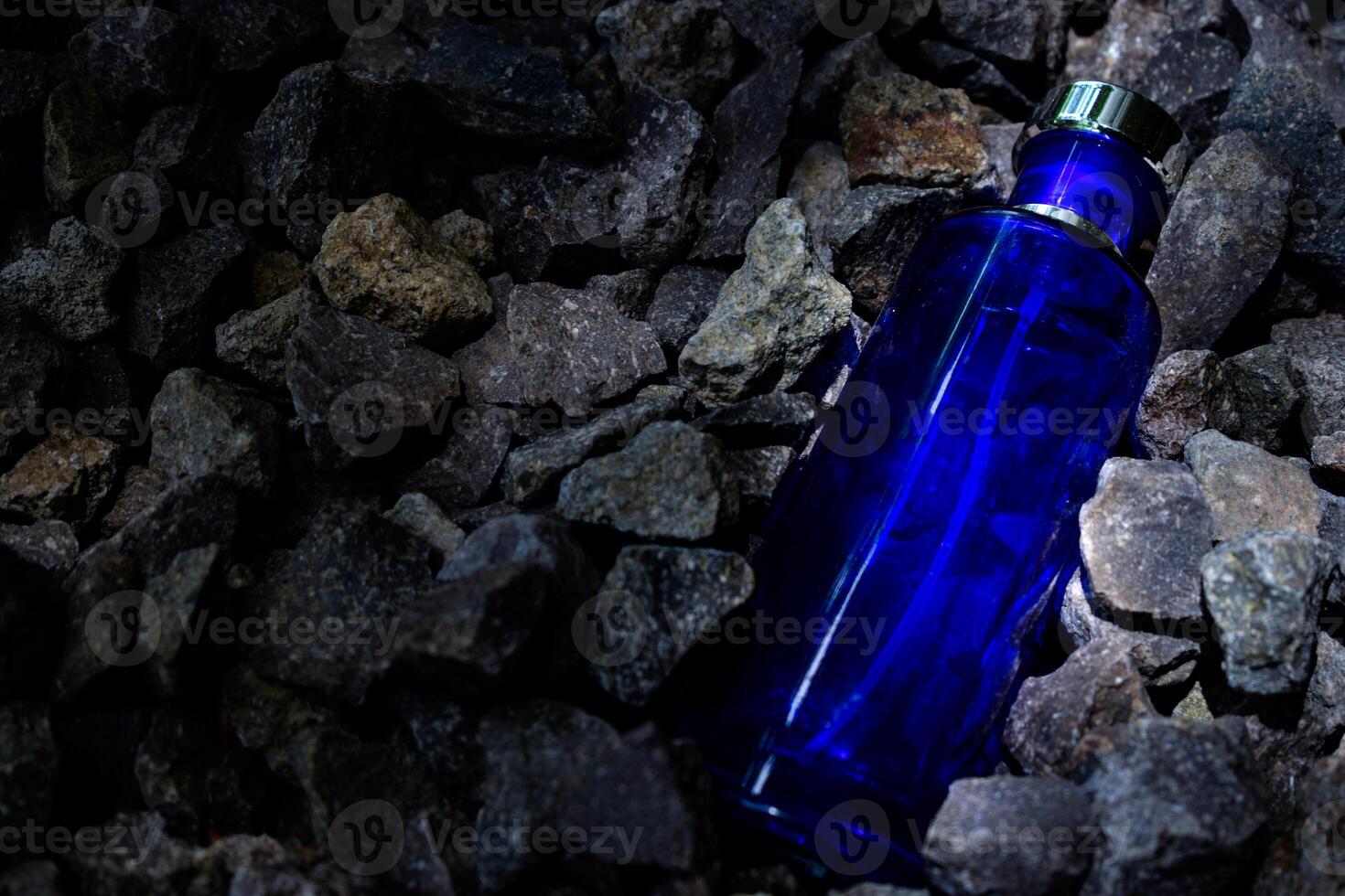 parfum foncé bleu transparent bouteille dans gravier ou corail Contexte photo