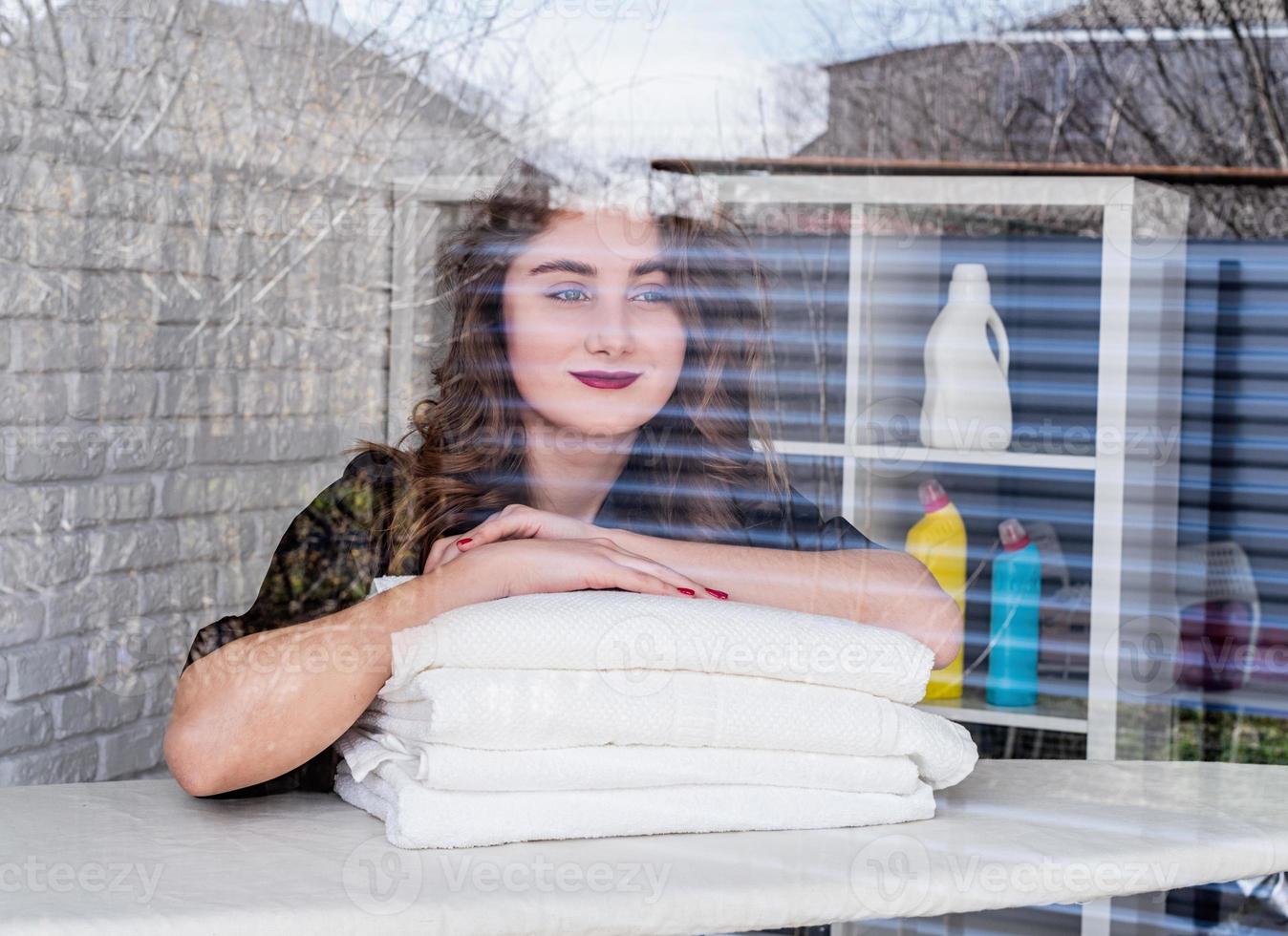 Souriante jeune femme sur un tas de serviettes sur fond de briques blanches photo