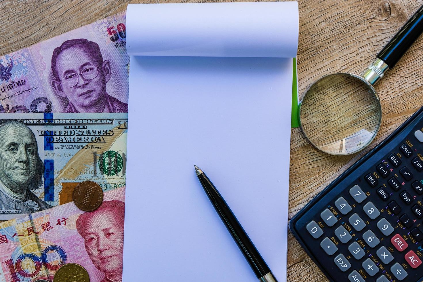 cahier vierge vide avec des billets de banque internationaux colorés et une calculatrice. photo