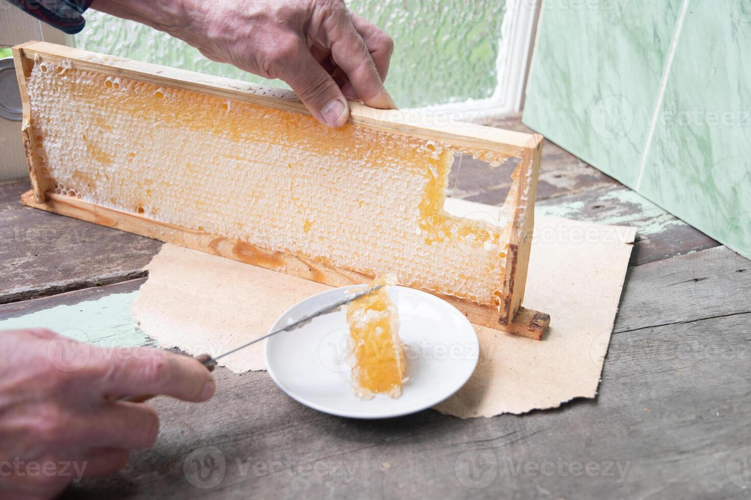 homme coupes nids d'abeille de une mon chéri Cadre avec une couteau pour en mangeant pour thé, mon chéri dans nids d'abeille est bien pour le santé photo