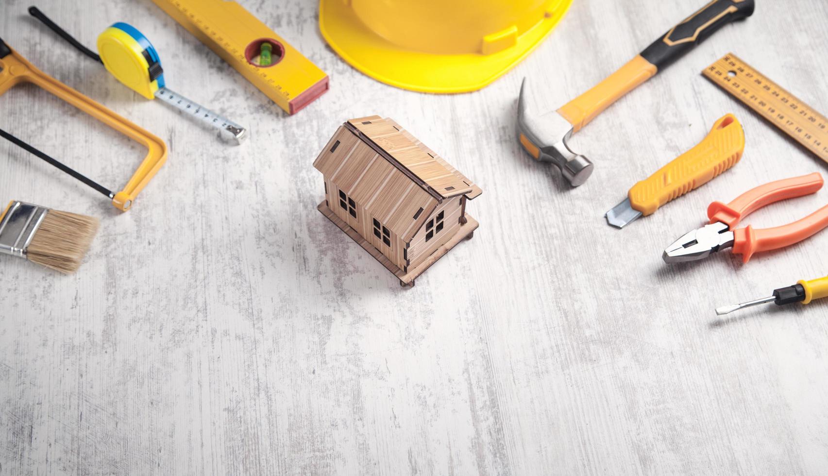 outils de travail avec un modèle de maison en bois. photo