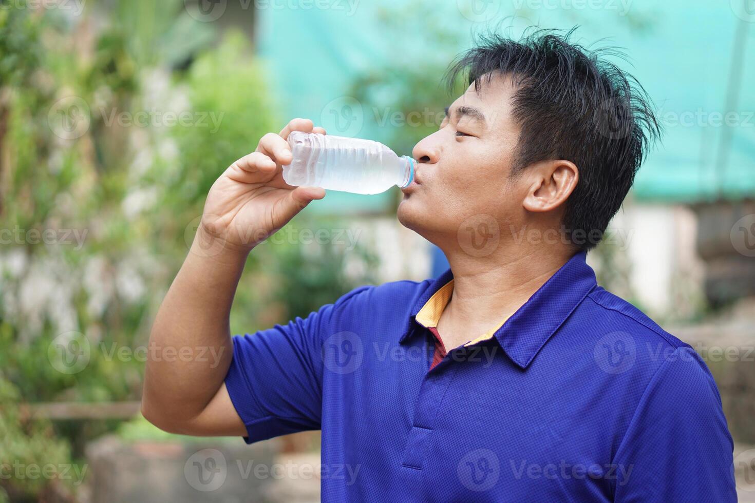 asiatique homme est en buvant cool l'eau de bouteille. concept, boisson l'eau pour bien santé. le soulagement de assoiffé, et protéger de chaleur accident vasculaire cérébral, cool vers le bas dans chaud temps condition. santé se soucier. photo