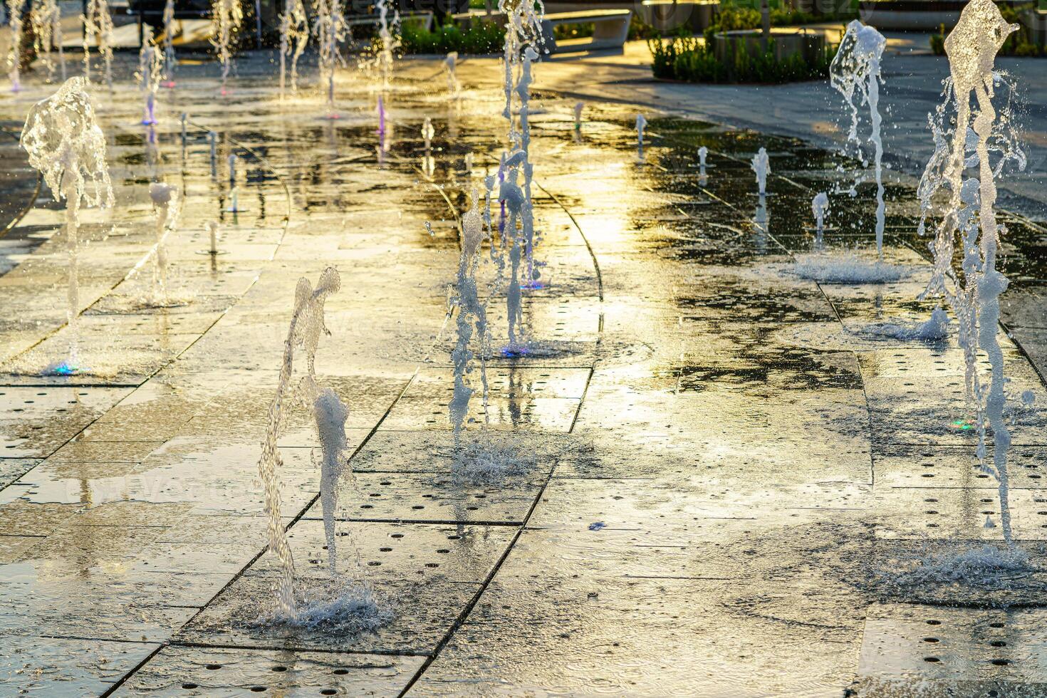 petit fontaines sur le trottoir, illuminé par lumière du soleil à le coucher du soleil ou lever du soleil à heure d'été. photo