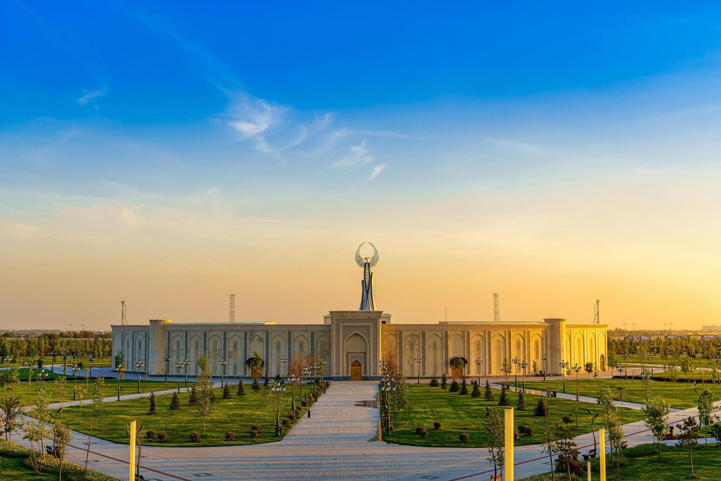 Ouzbékistan, Tachkent - avril 25, 2023 le territoire de le parc Nouveau Ouzbékistan avec monument de indépendance dans le forme de une stèle avec une humo oiseau à crépuscule. photo