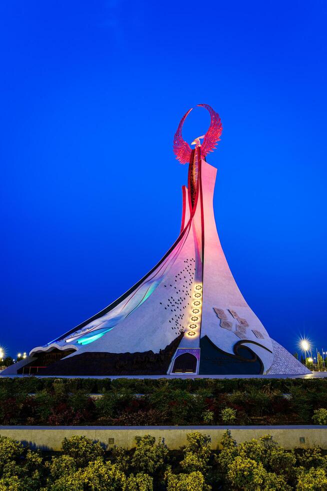 Ouzbékistan, Tachkent - mai 25, 2023 illuminé monument de indépendance dans le forme de une stèle avec une humo oiseau dans le Nouveau Ouzbékistan parc à la nuit. photo