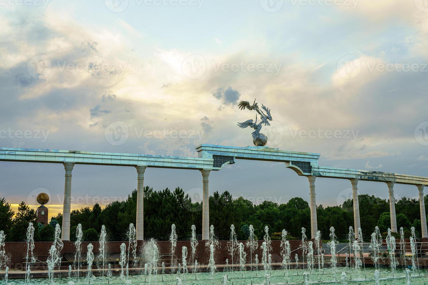 Mémorial et Lignes de fontaines illuminé par lumière du soleil à le coucher du soleil ou lever du soleil dans le indépendance carré à heure d'été, tachkent. photo