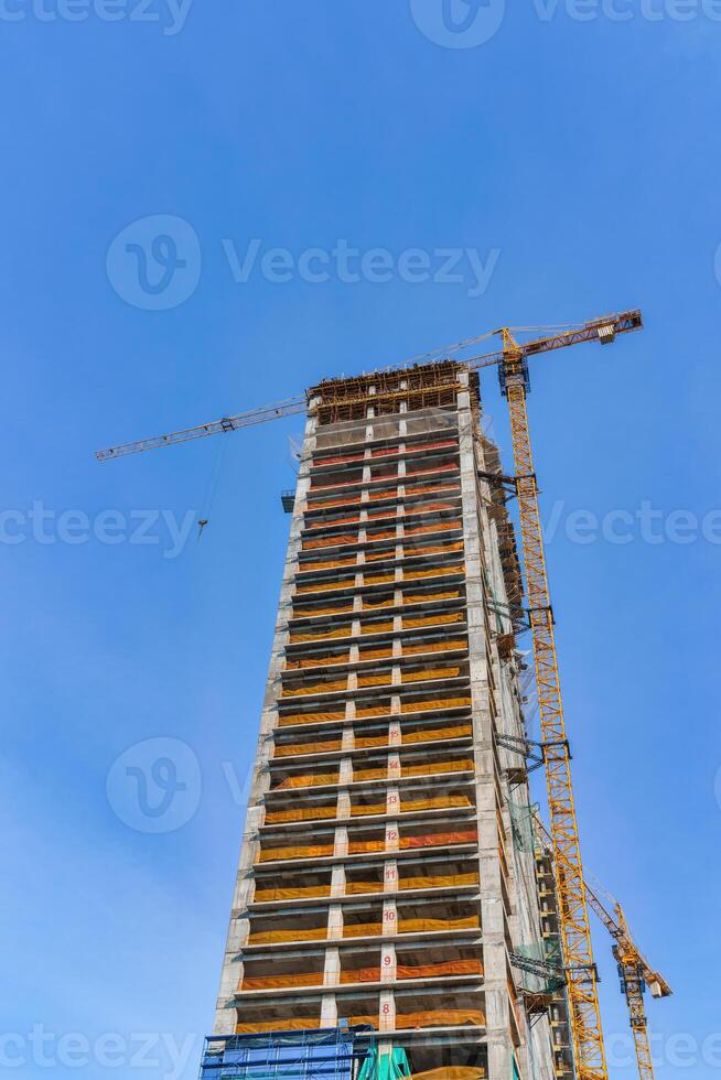 une grue bâtiment une gratte-ciel contre une bleu ciel. photo