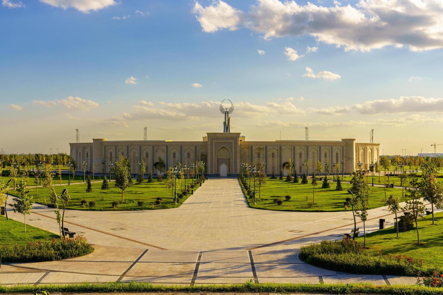 Ouzbékistan, Tachkent - octobre 4, 2023 le territoire de le parc Nouveau Ouzbékistan avec monument de indépendance dans le forme de une stèle avec une humo oiseau à le coucher du soleil. photo