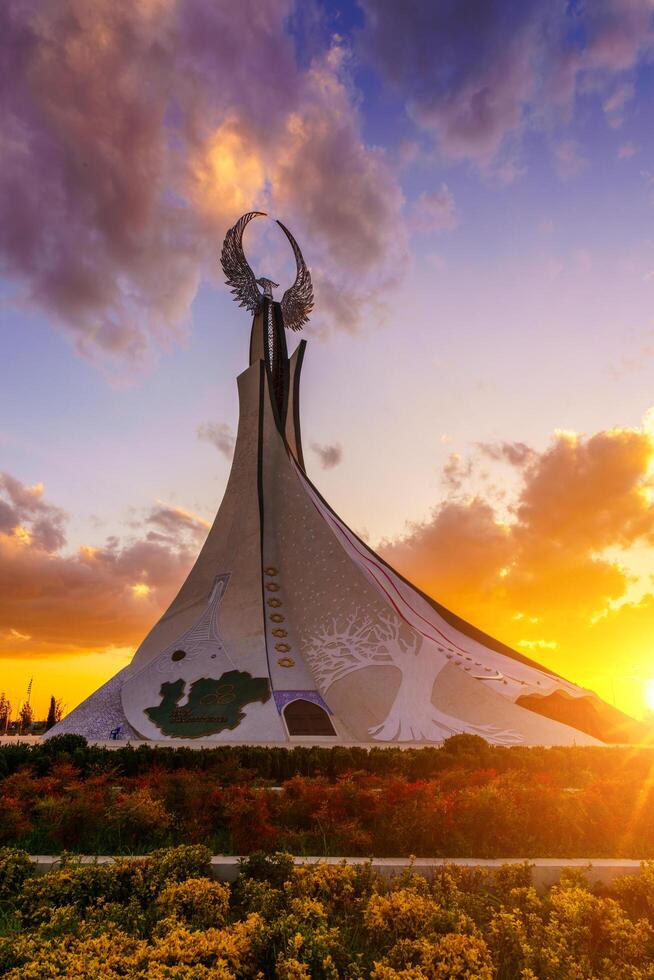 Ouzbékistan, Tachkent - octobre 4, 2023 monument de indépendance dans le forme de une stèle avec une humo oiseau sur une crépuscule avec Cliody ciel dans le Nouveau Ouzbékistan parc. photo