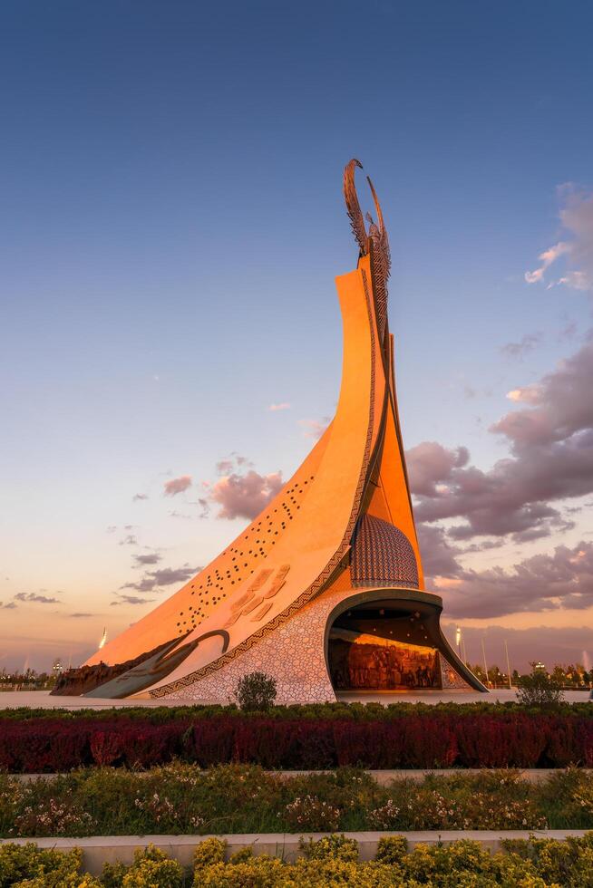 Ouzbékistan, Tachkent - octobre 4, 2023 monument de indépendance dans le forme de une stèle avec une humo oiseau sur une crépuscule avec Cliody ciel dans le Nouveau Ouzbékistan parc. photo