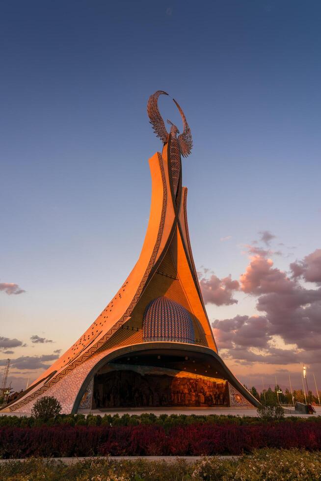 Ouzbékistan, Tachkent - octobre 4, 2023 monument de indépendance dans le forme de une stèle avec une humo oiseau sur une crépuscule avec Cliody ciel dans le Nouveau Ouzbékistan parc. photo