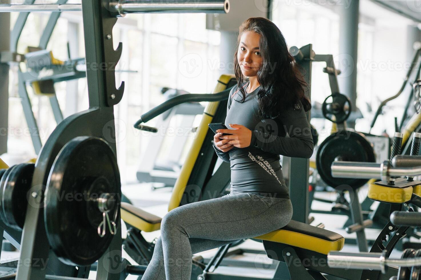 magnifique Jeune femme envoyer des SMS et social la mise en réseau tandis que dans une salle de sport. photo