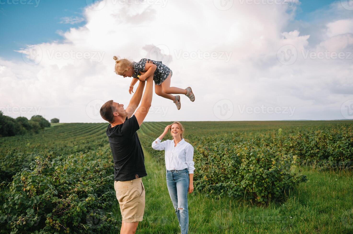 content famille avec peu fille dépenses temps ensemble dans ensoleillé champ. photo