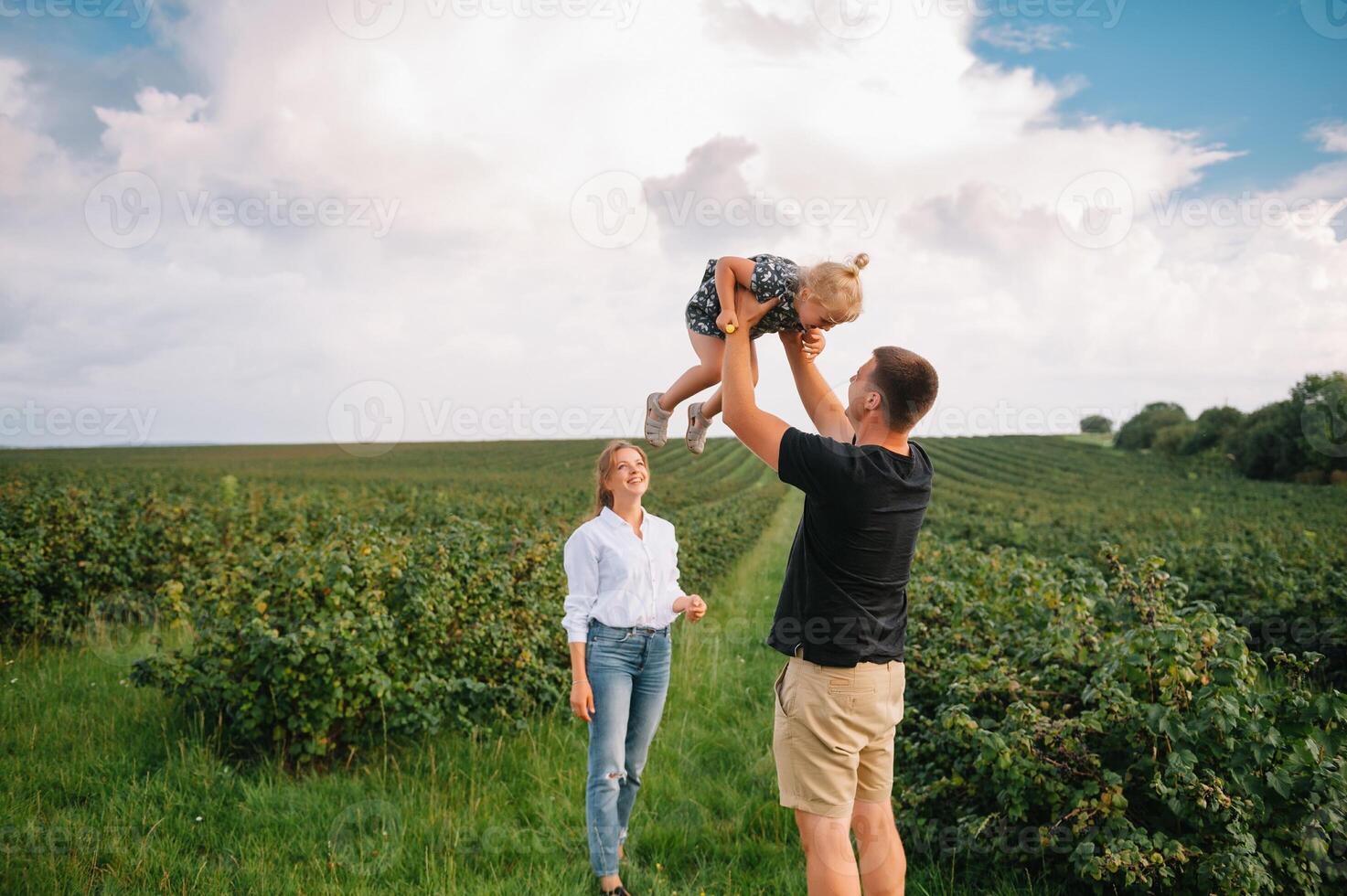 content famille en marchant dans le parc. maman, papa et fille marcher en plein air, Parents en portant le bébé les filles mains. enfance, la parentalité, famille obligations, mariage concept. photo