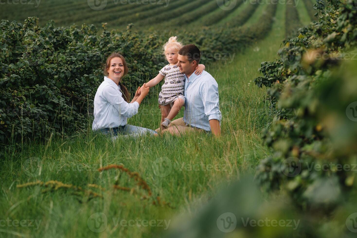 content famille avec peu fille dépenses temps ensemble dans ensoleillé champ. photo