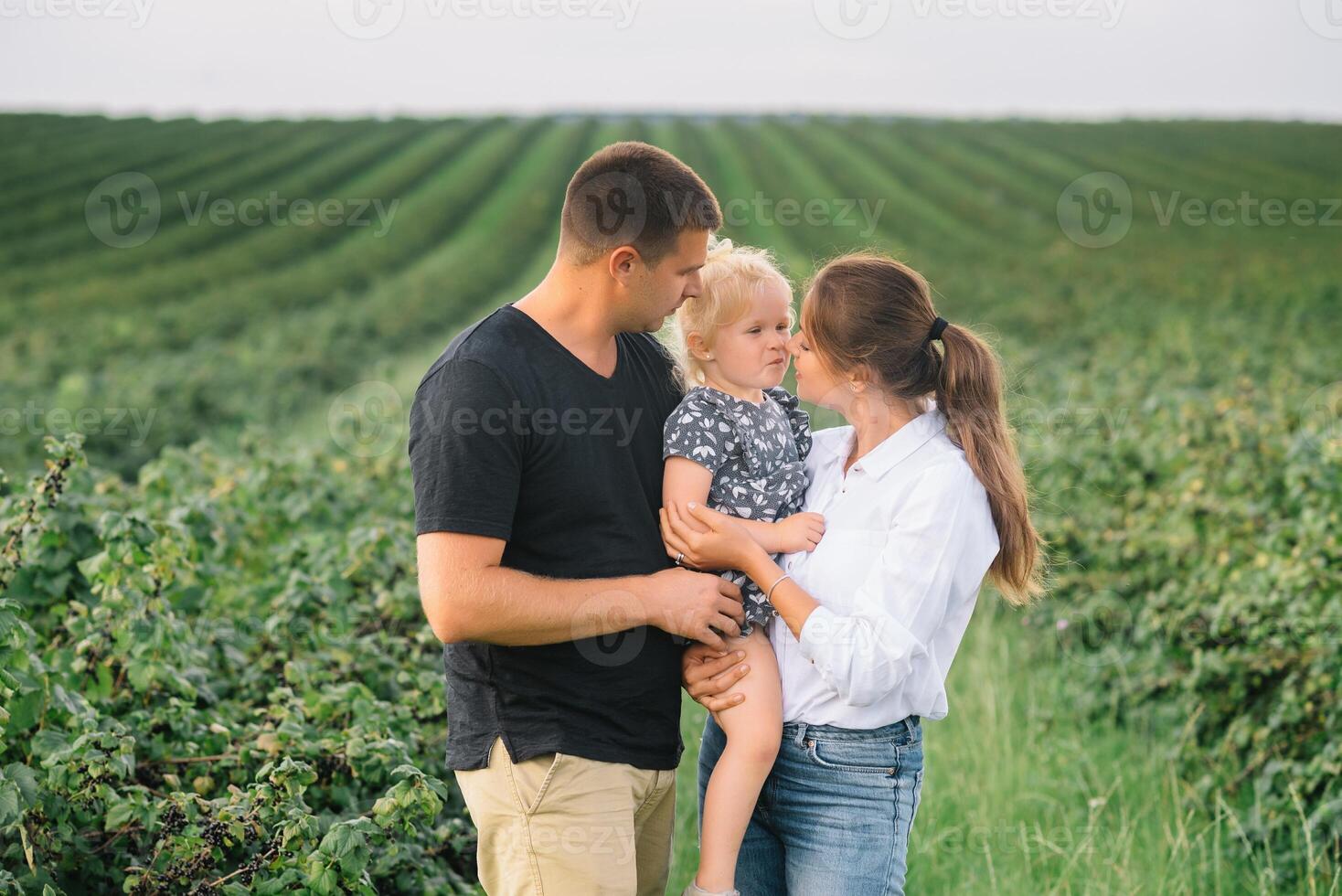 content famille en marchant dans le parc. maman, papa et fille marcher en plein air, Parents en portant le bébé les filles mains. enfance, la parentalité, famille obligations, mariage concept. photo