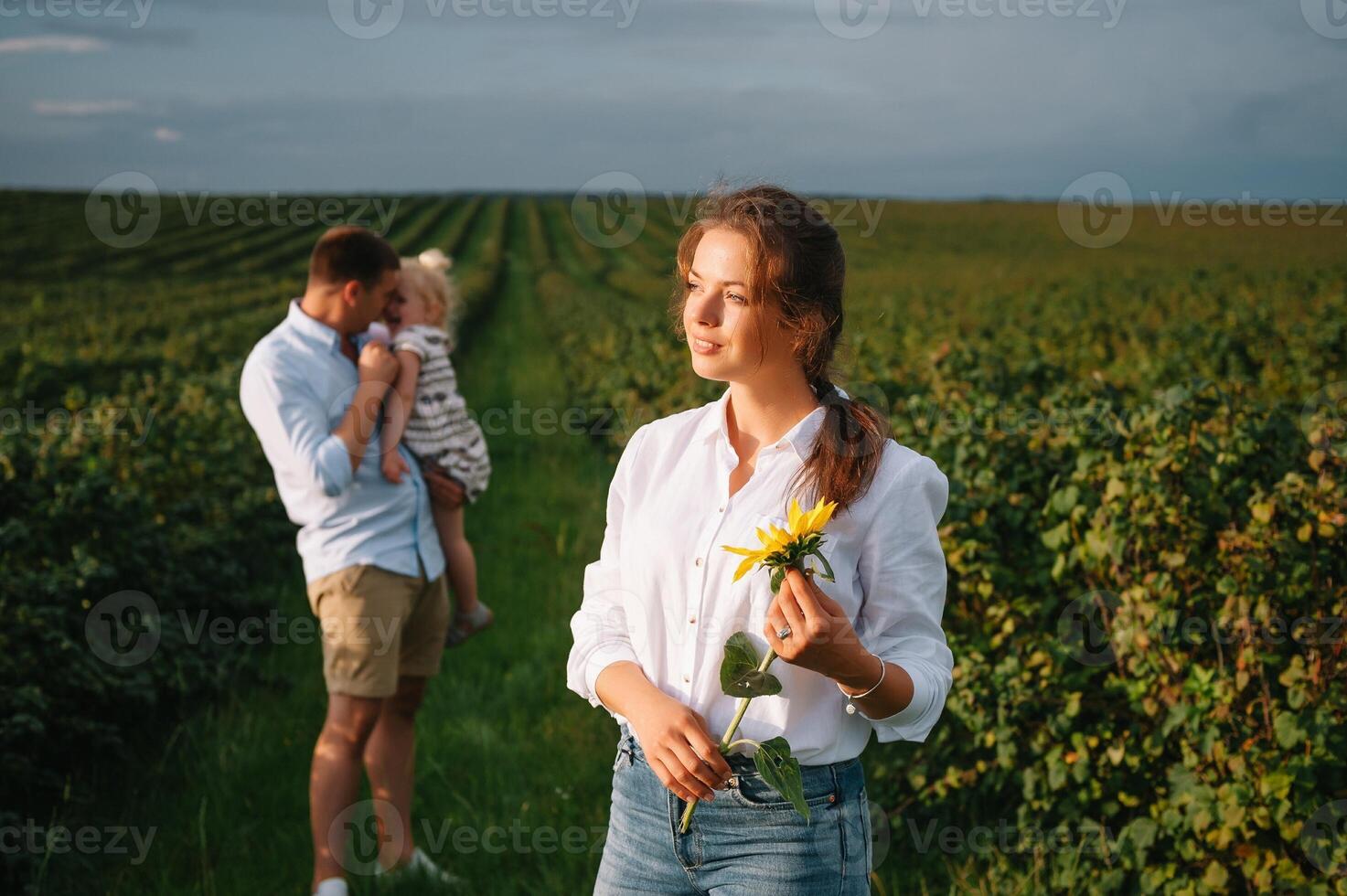 content famille avec peu fille dépenses temps ensemble dans ensoleillé champ. photo