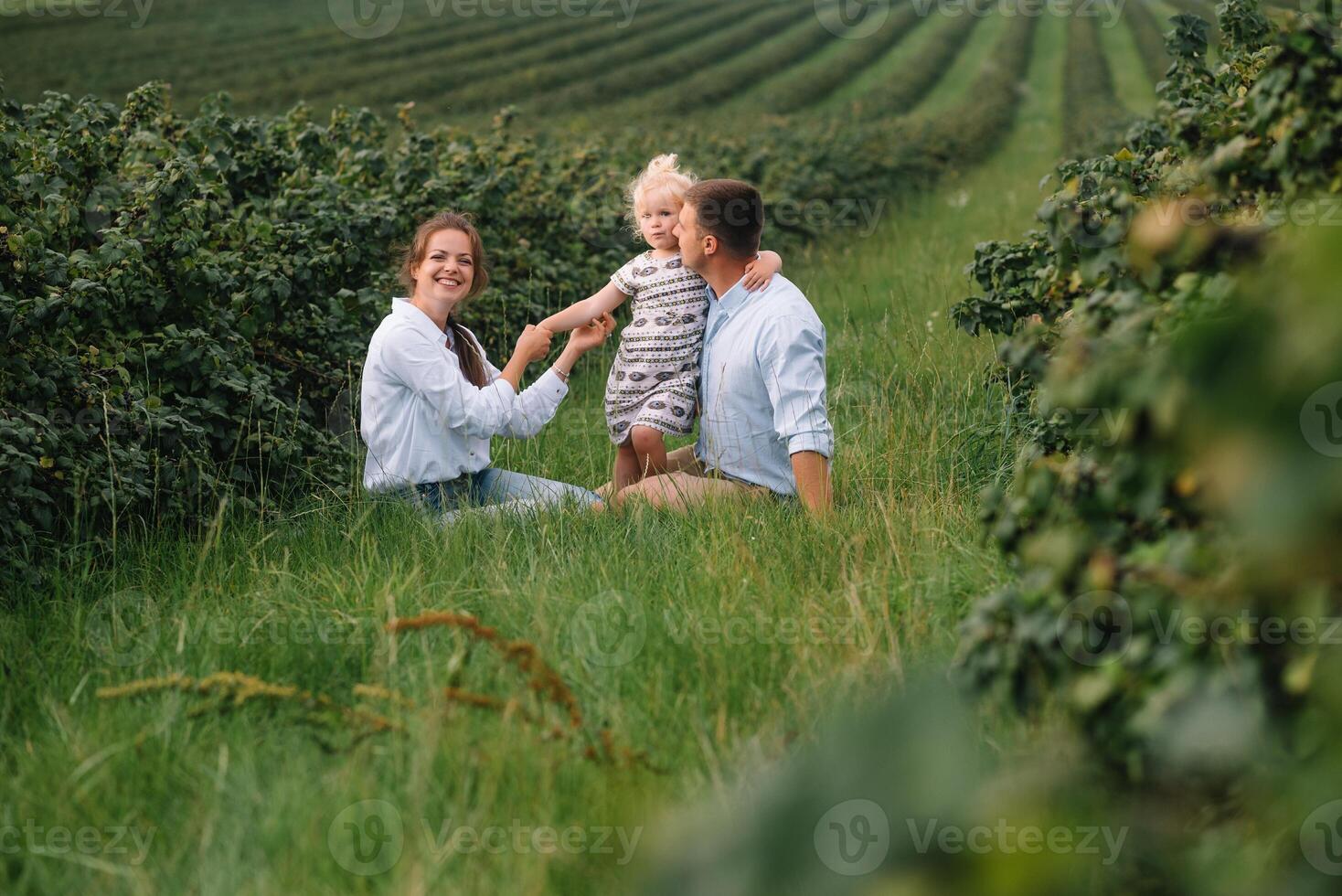 content famille avec peu fille dépenses temps ensemble dans ensoleillé champ. photo