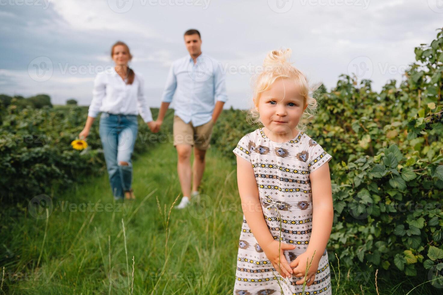 content famille avec peu fille dépenses temps ensemble dans ensoleillé champ. photo