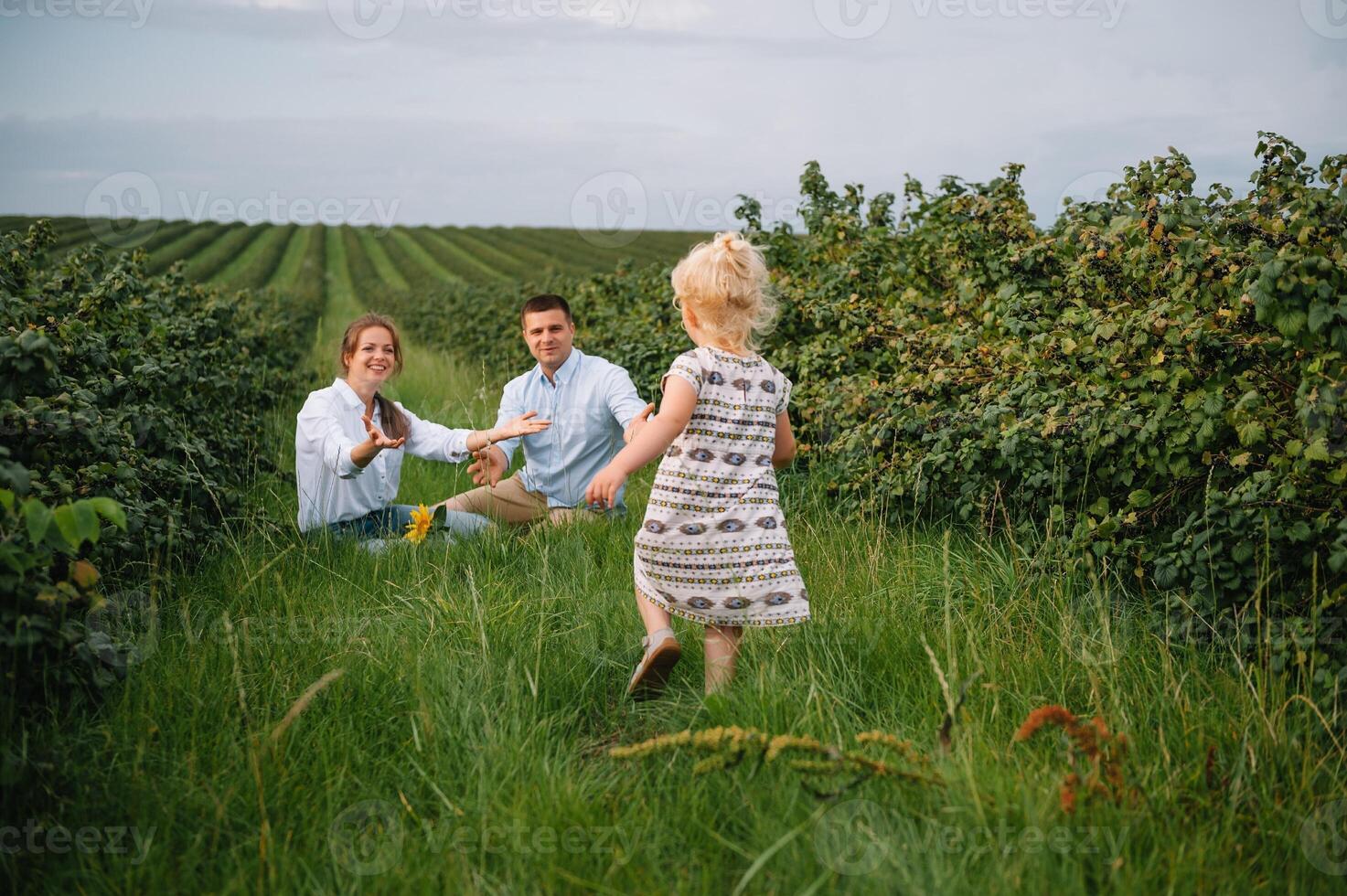 content famille en marchant dans le parc. maman, papa et fille marcher en plein air, Parents en portant le bébé les filles mains. enfance, la parentalité, famille obligations, mariage concept. photo