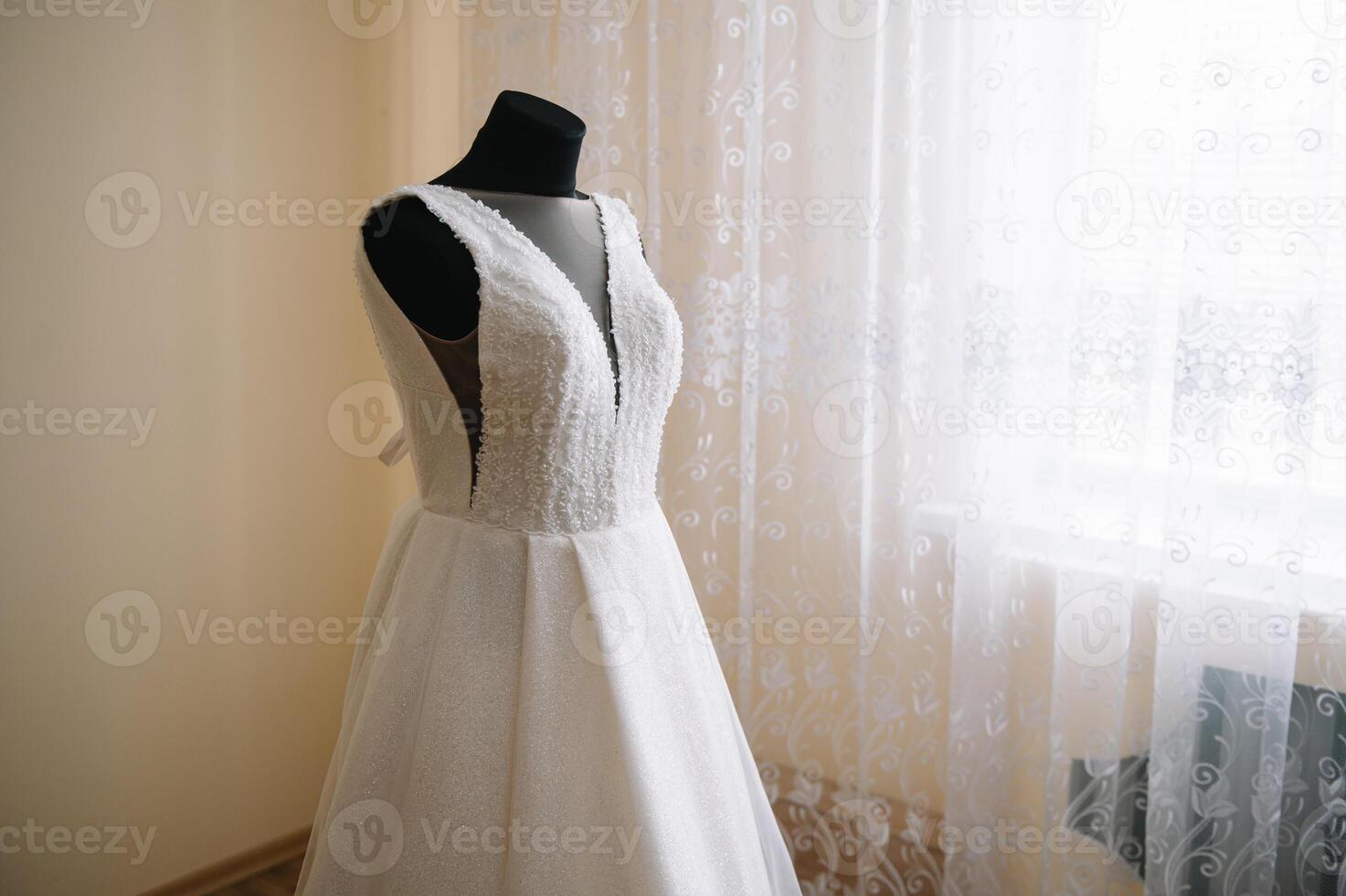 magnifique de la mariée blanc mariage robe bloque près le lit dans une Hôtel pièce avec fleurs à le bas. de mariée Matin avant la cérémonie photo