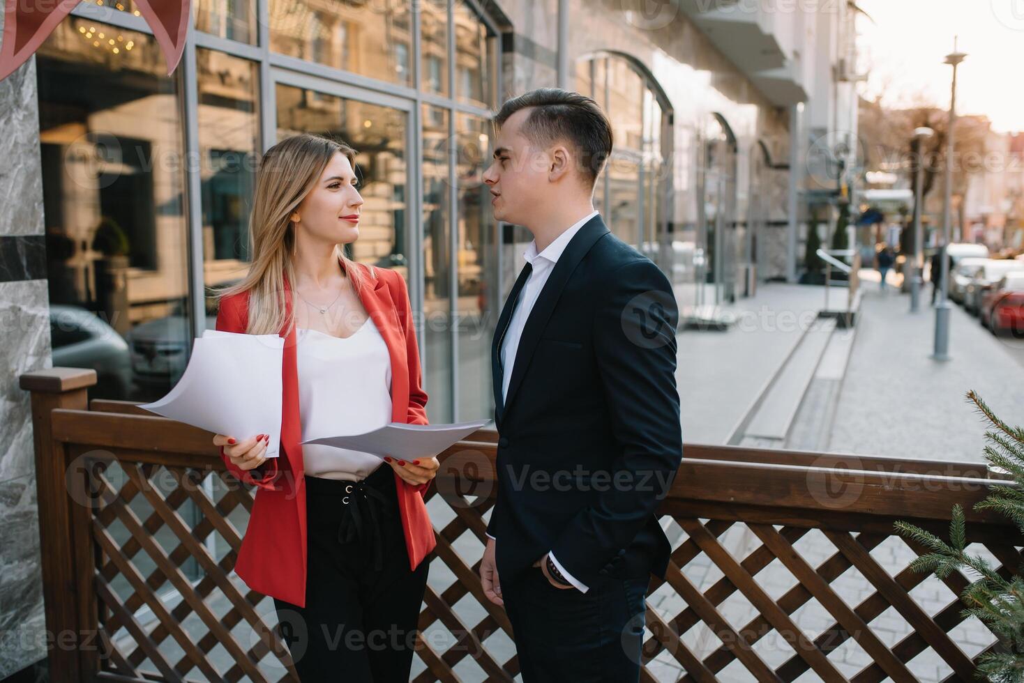 préparation pour réunion. deux Jeune affaires gens permanent à l'extérieur sur le ville rue en portant les documents à la recherche à chaque autre souriant content bas vue fermer. photo