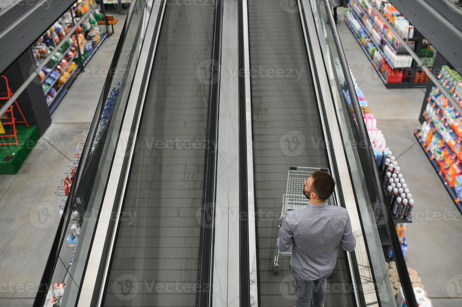 une homme avec une achats Chariot sur un escalier mécanique dans une Matériel magasin. photo