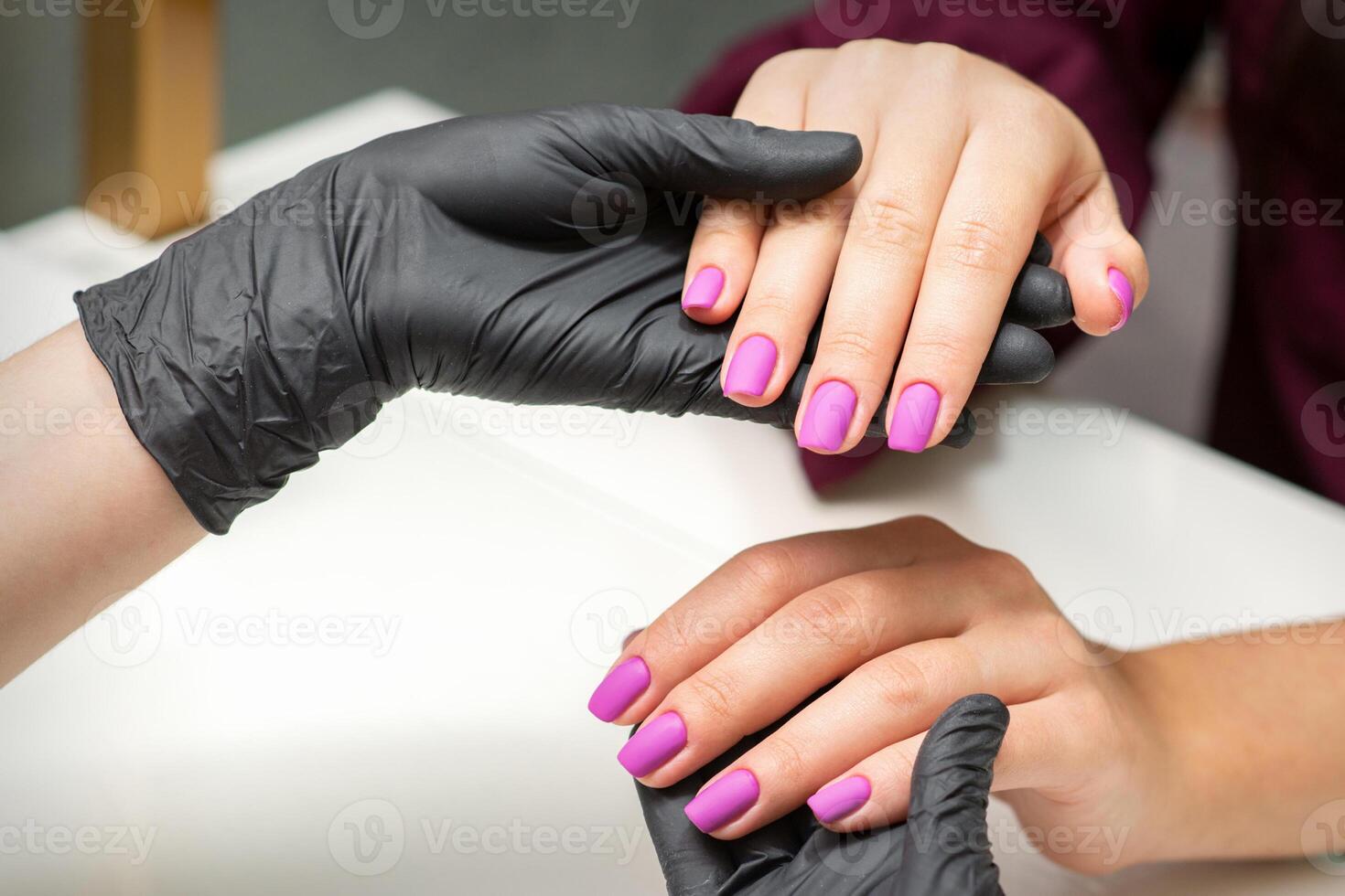 examen de manucuré les ongles. mains de manucure Maître dans noir gants examiner femelle rose ongles dans manucure salon. photo