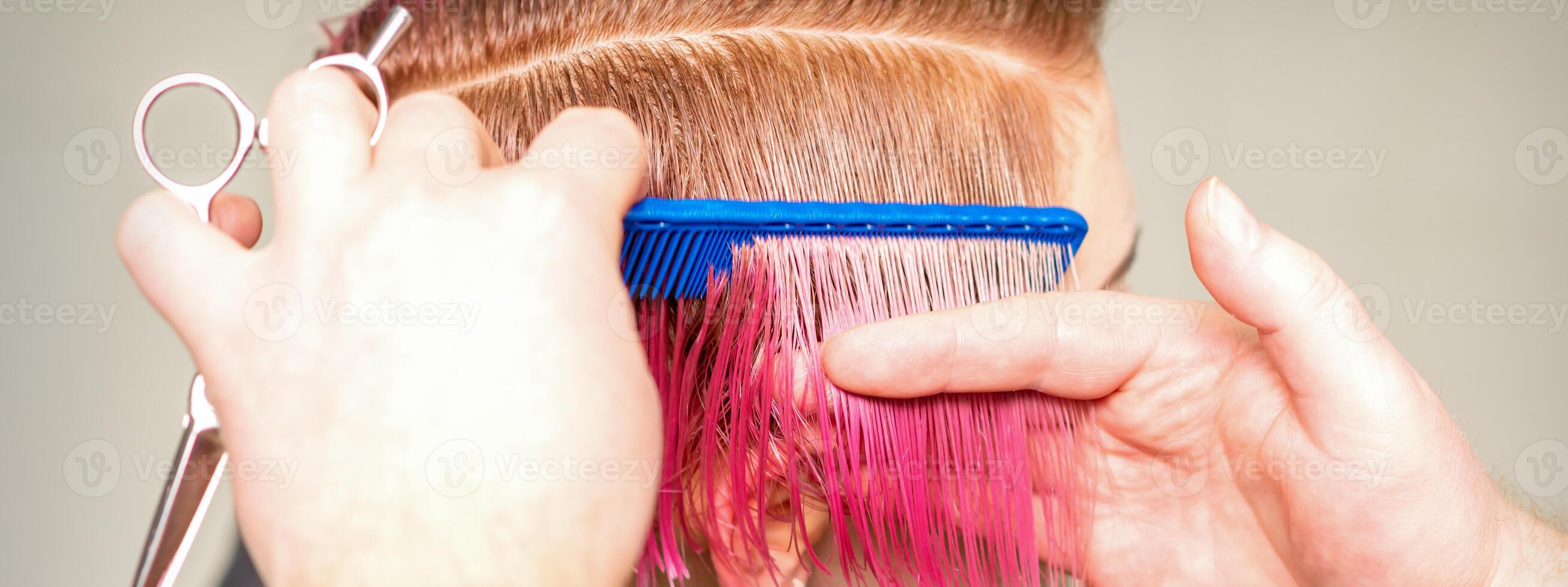 mains de coiffeur ratissage cheveux fabrication court rose coiffure pour une Jeune caucasien femme dans une beauté salon. photo