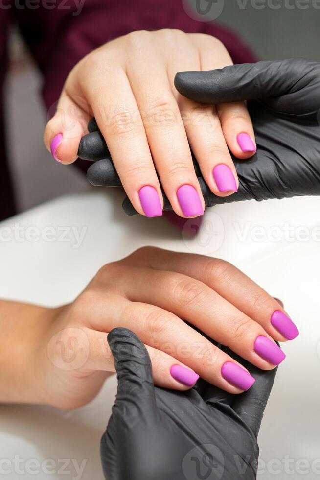 examen de manucuré les ongles. mains de manucure Maître dans noir gants examiner femelle rose ongles dans manucure salon. photo