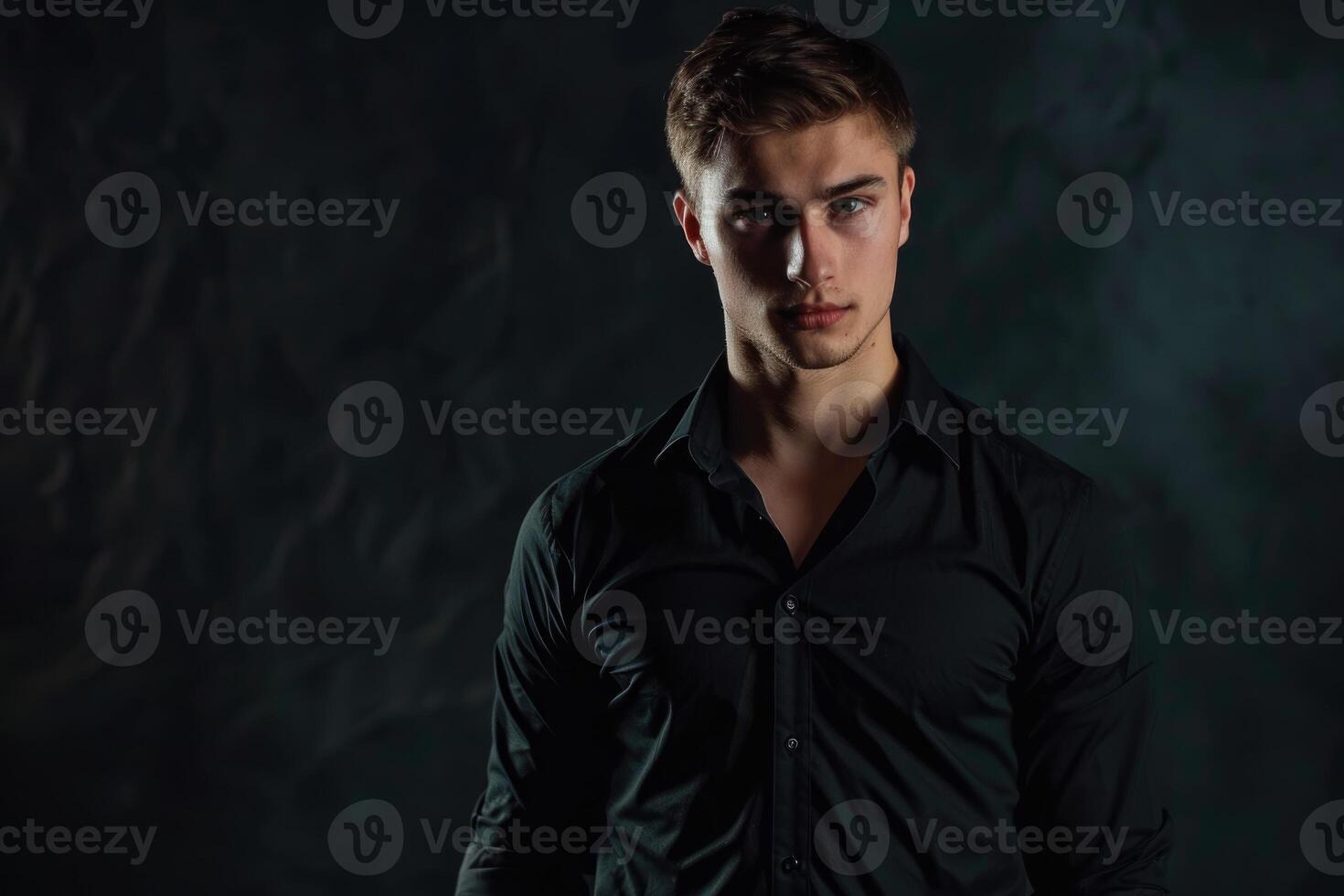 Beau homme dans noir chemise posant dans studio. photo