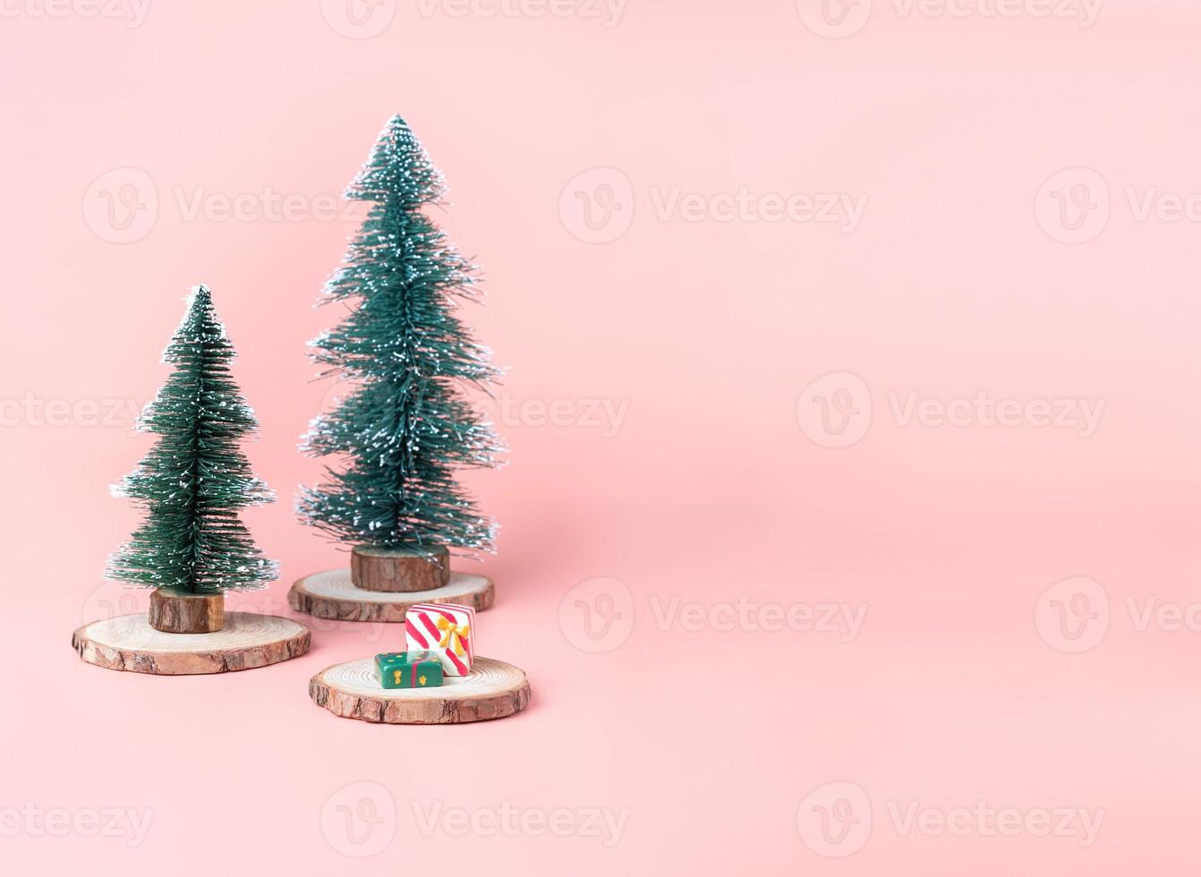arbre sapin de noël sur tranche de bûche de bois avec boîte présente sur rose pastel photo