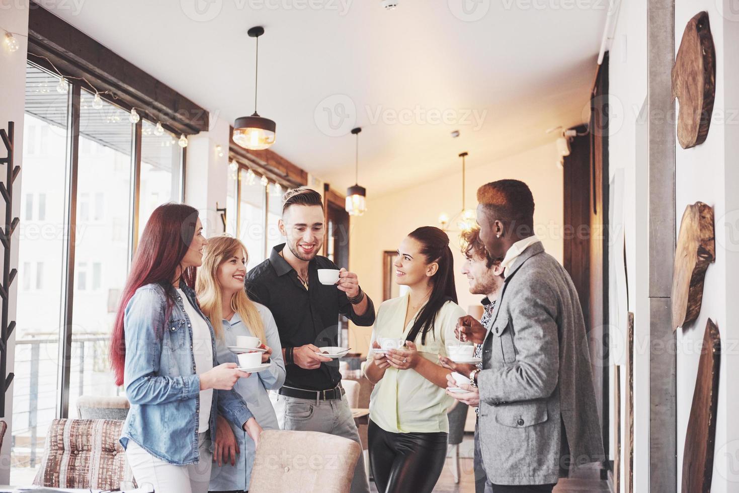 les jeunes gens d'affaires qui réussissent parlent et sourient pendant la pause-café au bureau photo