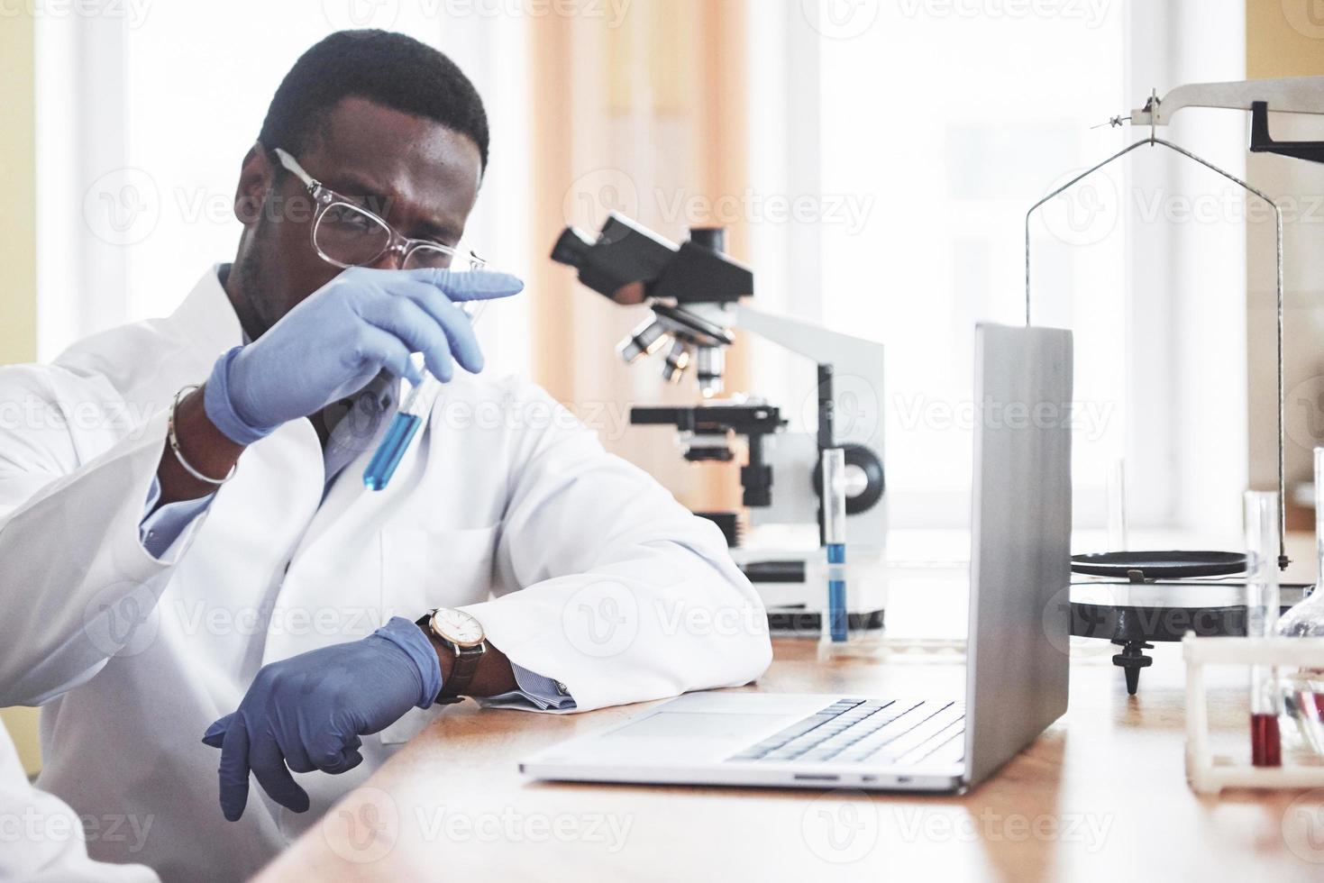 un travailleur afro-américain travaille dans un laboratoire menant des expériences. photo